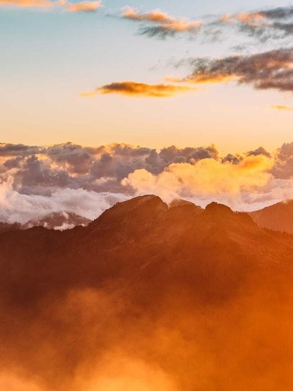 A figure in a flowing caped swimsuit running along a sandy beach, dress billowing in motion