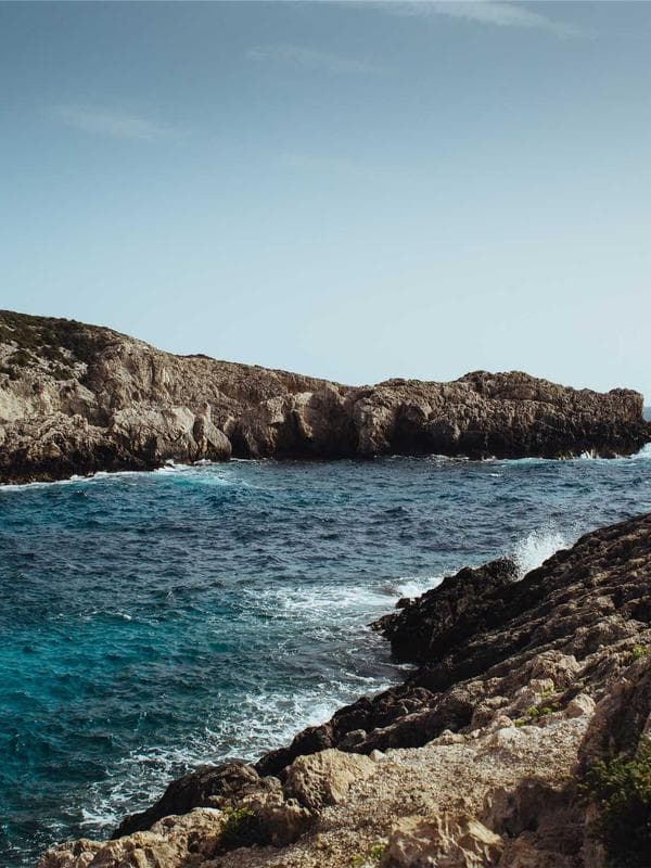 A model in a wide-collared cape, photographed from below against an open sky, arms extended