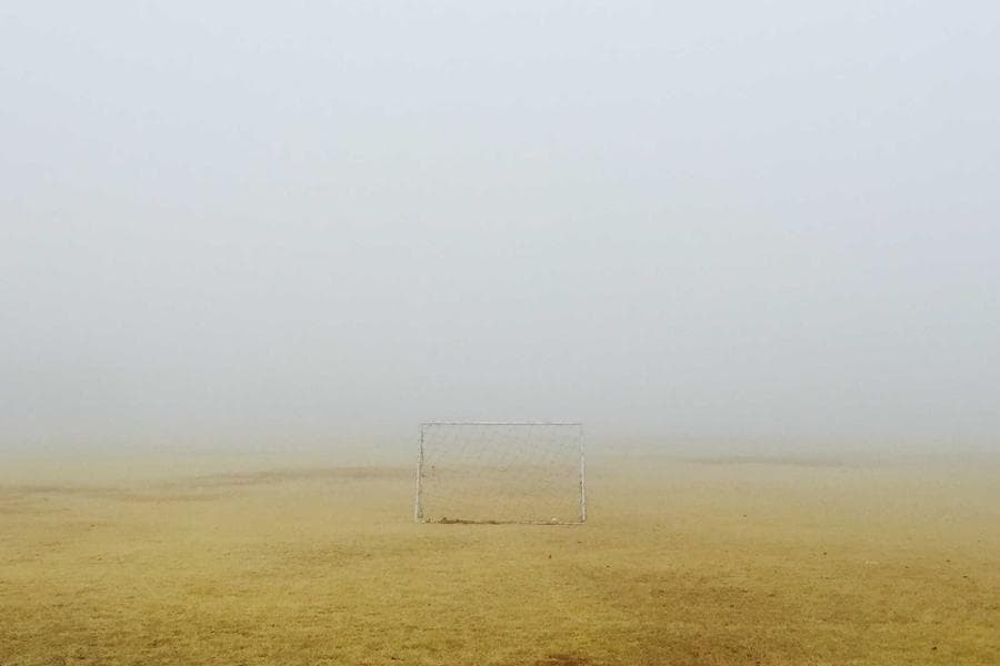 A tennis player photographed from above mid-serve, racquet extended, court geometry visible behind
